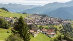 The image depicts a picturesque alpine town surrounded by mountains.